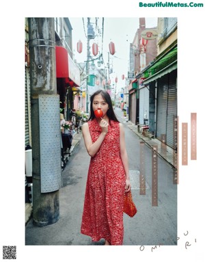 A woman in a red dress holding a plastic bag with goldfish in it.