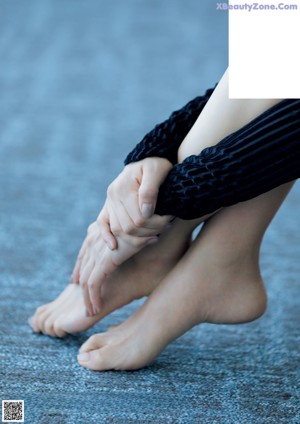 A woman sitting on the floor with her legs crossed.