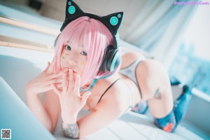 A woman with pink hair sitting on a white couch.