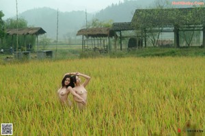 A naked woman holding an umbrella in a garden.