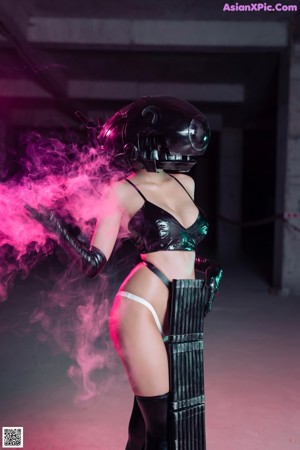 A woman in a black latex outfit holding a gun.