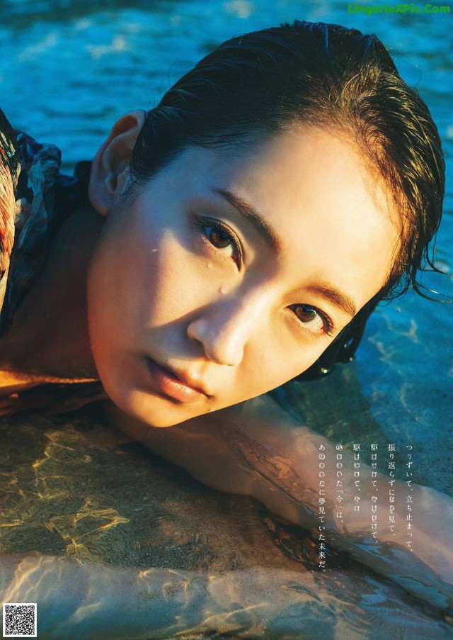 A woman laying in the water with her eyes closed.