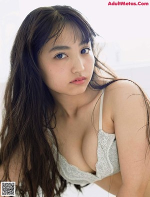 A woman in a white bra and panties sitting on a wooden floor.