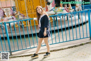 A woman in a school uniform leaning against a railing.
