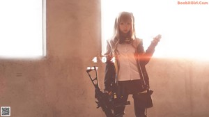 A woman in a black and yellow outfit holding a gun.