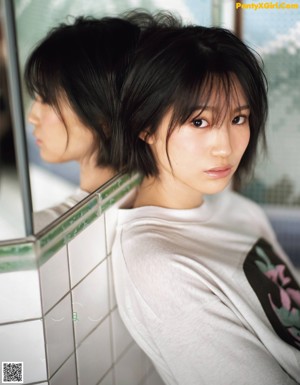 A woman wearing a white shirt with a pink and brown design on it.