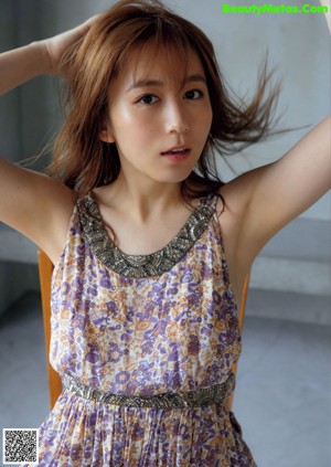 A woman in a blue tank top holding a purple flower.