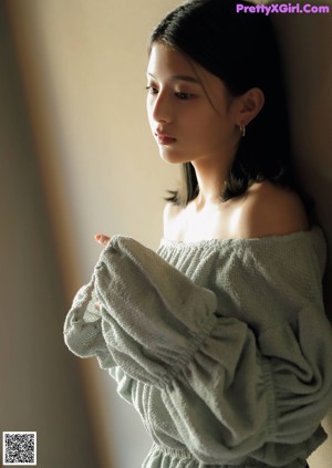 A woman in a gray sweater and black shorts posing for a picture.