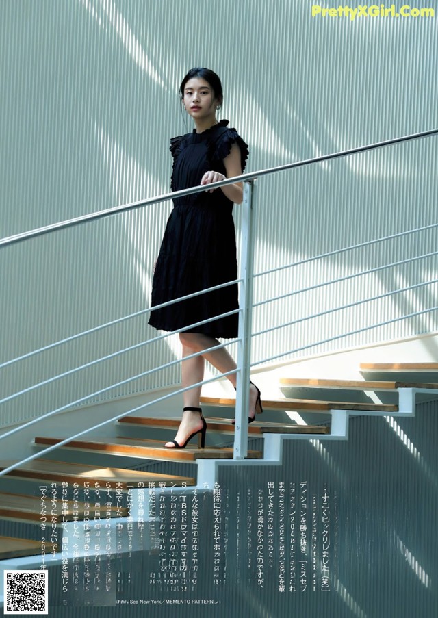 A woman in a black dress standing on a set of stairs.