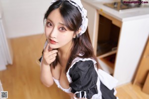 A woman in a maid outfit sitting on a bench.