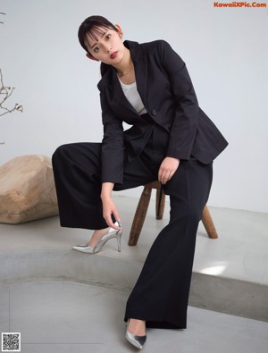 A woman sitting on a chair with her hand on her chin.