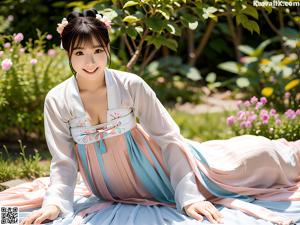 A woman wearing a blue and pink hanbok standing next to flowers.