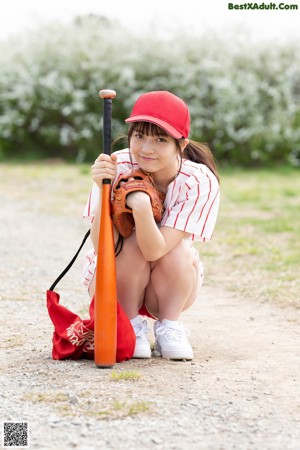 A woman wearing a baseball uniform and a red hat.