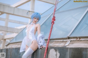 A woman in a white dress sitting on a metal structure.