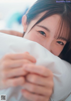 A woman laying in bed with a pillow covering her face.