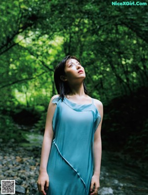 A woman in a red dress standing on a dirt road.