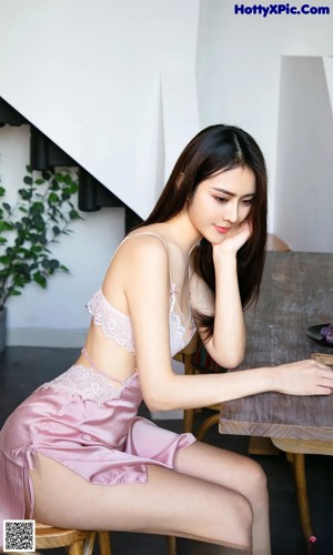 A woman in a pink lingerie sitting at a table.