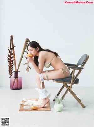 A woman in white lingerie sitting on a rug next to a glass of milk.