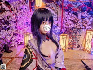 A woman in a kimono sitting on the floor next to a lamp.