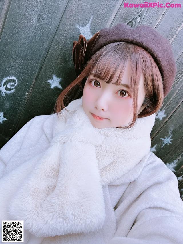 A young girl wearing a white coat and a brown hat.