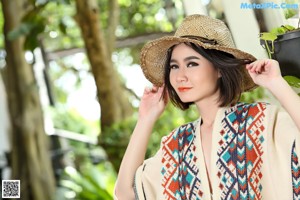 A woman wearing a straw hat and a colorful shawl.