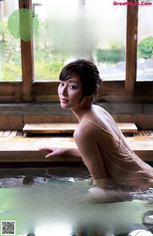 A woman in a bathtub in the middle of a room.