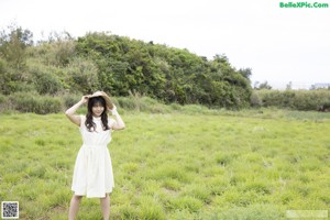 A woman in a white dress standing in a field.