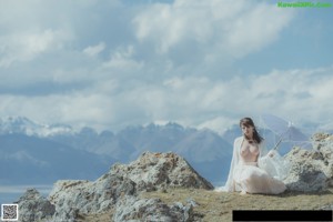 A woman standing on top of a mountain next to the ocean.