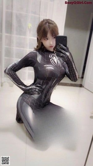 A woman in a spiderman suit taking a selfie.