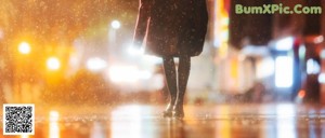 A woman standing in the rain holding an umbrella.