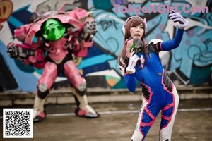 A woman in a blue and green outfit sitting on top of a pink car.