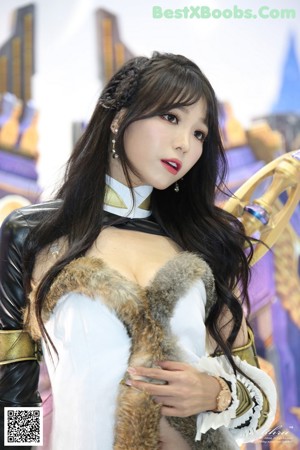 A woman in a white and black outfit holding a fan.