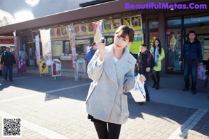 A woman in a gray coat holding a large umbrella.