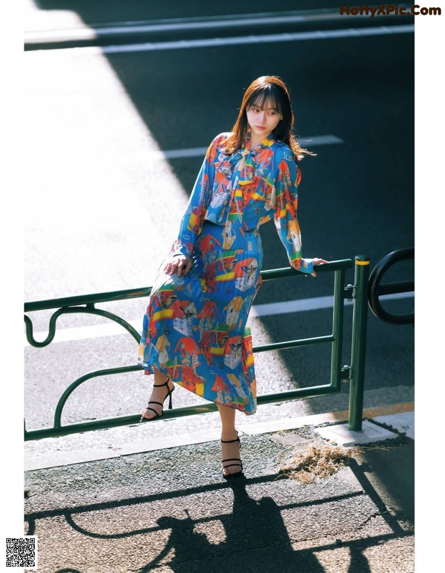 A woman in a blue dress is standing on a railing.