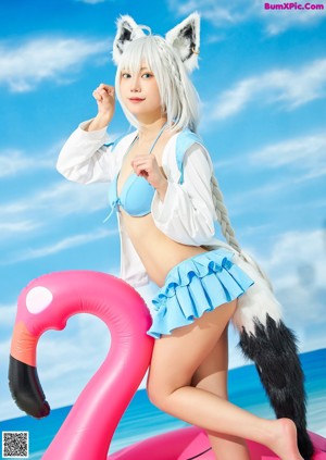 A woman in a sailor outfit holding an umbrella on the beach.