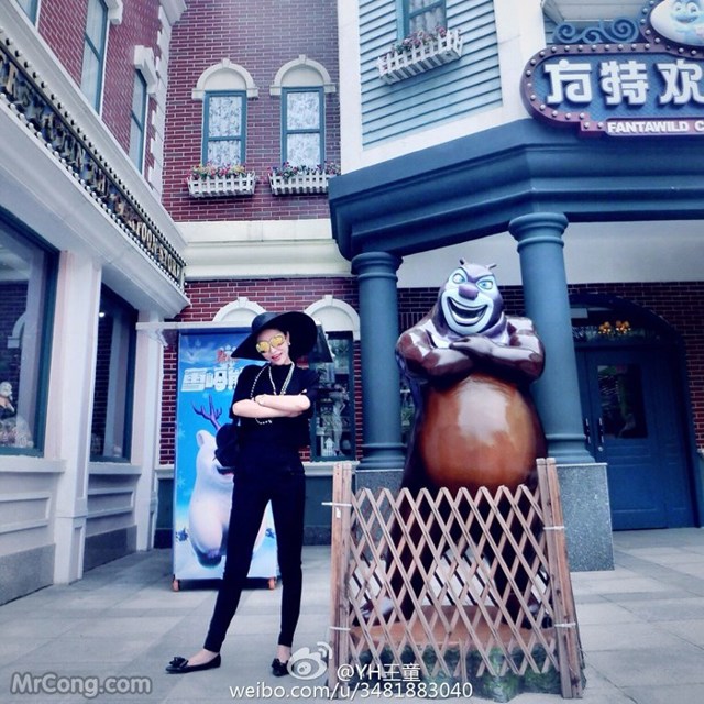 A woman standing in front of a building with a giant bear statue.