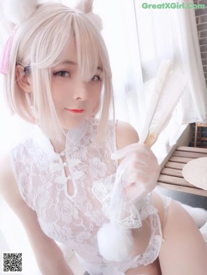 A woman in a white lingerie sitting on a window sill.